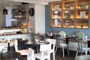 a dining room with tables and chairs and a bar at Hôtel de la Baie in Crozon