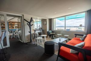 a living room with a red couch and chairs and windows at Hôtel de la Baie in Crozon