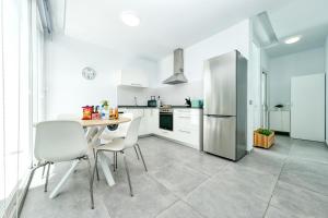 a white kitchen with a table and a refrigerator at Karma Famara 2 25m del mar in Famara