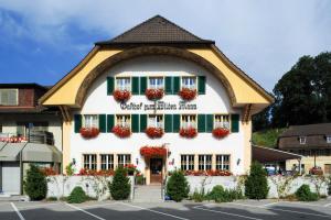 un bâtiment avec des volets verts et des fleurs rouges dans l'établissement Gasthof zum Wilden Mann, à Aarwangen