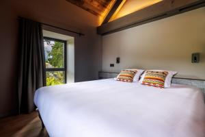 ein Schlafzimmer mit einem großen weißen Bett mit zwei Kissen in der Unterkunft Pyrénées Prestige - Villas d'exceptions et hébergements insolites in Argelès-Gazost