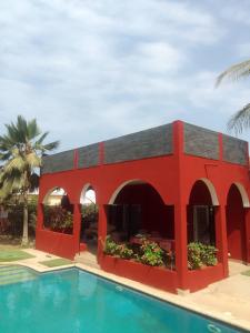 a red building next to a swimming pool at Villa Ty an heol in Ngaparou