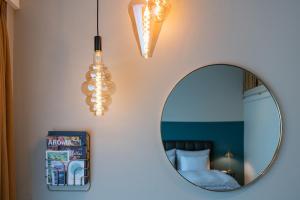 un miroir et des lumières sur un mur à côté d'un lit dans l'établissement Hotel Schweizerhof Lenzerheide, à Lenzerheide