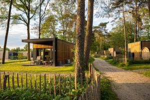 een klein huis in het bos met een hek bij Hofparken Wiltershaar in Kotten