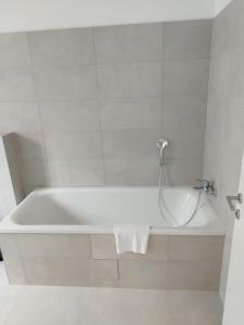 a white bath tub in a white tiled bathroom at Haus mit Garten bei Wien in Langenzersdorf