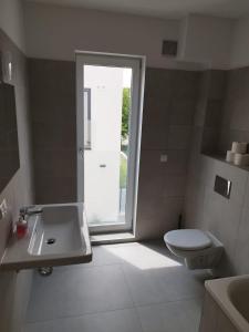 uma casa de banho com um WC, um lavatório e uma janela em Haus mit Garten bei Wien em Langenzersdorf