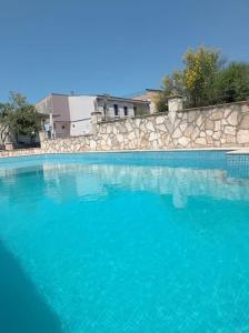 a swimming pool with blue water and a stone wall at Villa Mona Liza in Dobra Voda