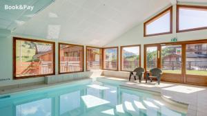 uma piscina com duas cadeiras num quarto com janelas em Le Goléron des Evettes em Flumet