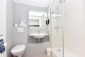 La salle de bains blanche est pourvue de toilettes et d'un lavabo. dans l'établissement Hôtel Kyriad La Rochelle Centre Ville, à La Rochelle