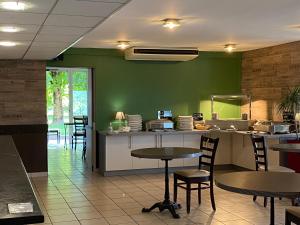 ein Restaurant mit grünen Wänden, Tischen und Stühlen in der Unterkunft Brit Hotel Reims La Pompelle in Reims