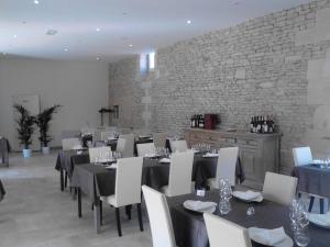 a dining room with tables and chairs and a brick wall at Auberge De La Luzerne in Bernières-sur-Mer