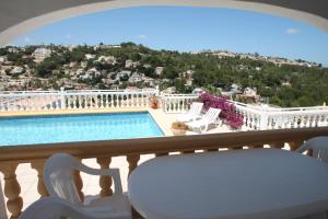 a balcony with a table and chairs and a swimming pool at Paraiso Terrenal 4 - well-furnished villa with panoramic views by Benissa coast in Fanadix