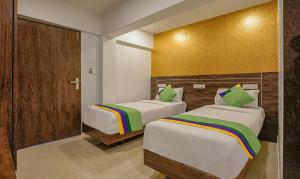 two beds in a hotel room with yellow walls at Treebo Atithi Inn Malad in Mumbai +28 photos