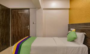 a bedroom with a bed with a green pillow on it at Treebo Trend Atithi Inn in Mumbai