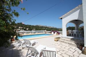 a group of white chairs sitting next to a swimming pool at Paraiso Terrenal 4 - well-furnished villa with panoramic views by Benissa coast in Fanadix