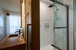 a bathroom with a glass shower and a sink at Moxy Virginia Beach Oceanfront in Virginia Beach +18 photos