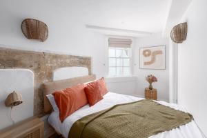 ein weißes Schlafzimmer mit einem Bett mit orangefarbenen Kissen in der Unterkunft Newly Renovated City Apartment in Bath