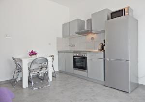 eine Küche mit einem Tisch und einem Kühlschrank sowie einem Tisch und Stühlen in der Unterkunft Rooms&Apartments Beach Star in Split