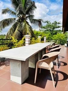 a large concrete table with chairs and a palm tree at Otha Shy Airport Transit Hotel in Katunayaka