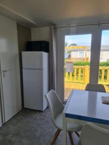 een keuken met een tafel en een koelkast en een balkon bij Mobil-home Magnolia 300m de la plage Ambleteuse in Ambleteuse