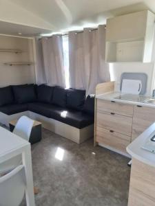 een woonkamer met een bank en een keuken bij Mobil-home Magnolia 300m de la plage Ambleteuse in Ambleteuse