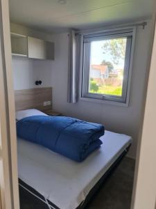 een slaapkamer met een blauw bed en een raam bij Mobil-home Magnolia 300m de la plage Ambleteuse in Ambleteuse