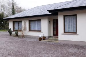 a white house with two windows and a driveway at Killarney , Ring of Kerry 2 Bed Apartment 2 Bathrooms in Killarney