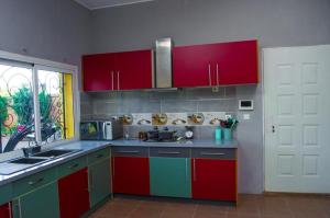 una cocina con armarios rojos y verdes y fregadero en Room in Villa - The blue room is an accent of modernity in the silence of the surrounding garden, en Antananarivo