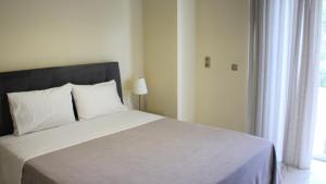Schlafzimmer mit einem Bett mit weißer Bettwäsche und einem Fenster in der Unterkunft SUNSET Luxury Accommodation in Verga Kalamata