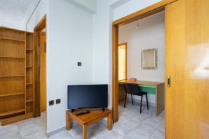 Zimmer mit einem TV, einem Tisch und einem Schreibtisch. in der Unterkunft Cozy Apartment 2 in Sitia