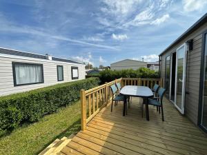 a wooden deck with a table and chairs on it at O'hara mobil-home haut de gamme à 300m de la plage in Ambleteuse