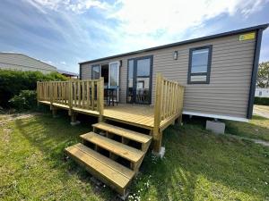a large deck with a table and chairs on a tiny house at O'hara mobil-home haut de gamme à 300m de la plage in Ambleteuse +13 photos