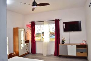 1 dormitorio con cortinas rojas y ventana en Room in Villa - The romantic atmosphere of the red room to discover the pleasure of a stay, en Antananarivo