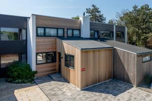 une maison avec un garage en bois devant elle dans l'établissement Lepelblad 42, Nieuwvliet, à Nieuwvliet