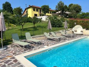 een groep stoelen en parasols naast een zwembad bij Agriturismo Tre Tigli in Asti