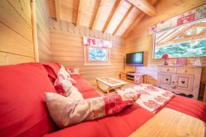 - une chambre avec un lit rouge dans une cabane en bois dans l'établissement Chalet Cafourotte, au calme, SPA, à Gérardmer