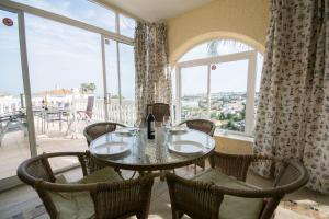 a dining room with a table and chairs and windows at Villa Janina in Fuengirola