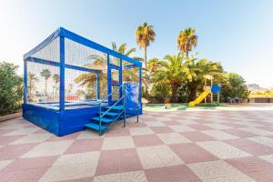 un parque infantil con una jaula azul y un tobogán en Lovely Port Europa 1 Bedroom apartment 2 Adults 1 Child, en Calpe