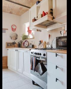 a kitchen with white cabinets and a stove with towels at Terracielo Ramona B&B Homestay Penne in Penne