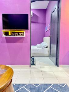 a room with a pink wall with a tv at AISY HOMESTAY - Rumah 2 atau 3 in Kampong Tanjong Karang +17 photos