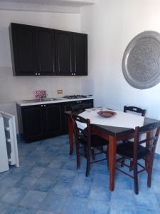 a kitchen with a table and chairs and black cabinets at Villa Lucia in Lampedusa