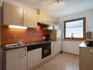 cocina con armarios de madera, fregadero y ventana en Appartement Elisabeth, en Ramsau im Zillertal