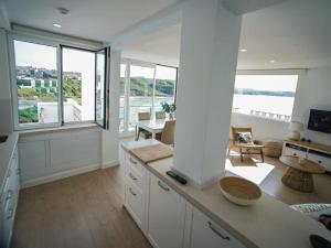 a kitchen with white cabinets and windows and a table at Apartamento Sunset con vistas Playa de Los Locos in Suances