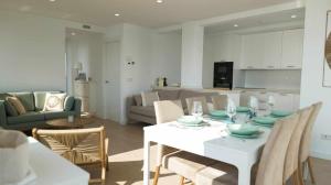 a kitchen and living room with a white table and chairs at Apartamento Sunset con vistas Playa de Los Locos in Suances