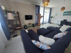 uma sala de estar com um sofá azul e uma televisão em Bajcsyház Apartman em Keszthely