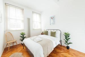 a white bedroom with a bed and a chair at Unique 2 Bedroom Flat on Stoke Newington High Street in London