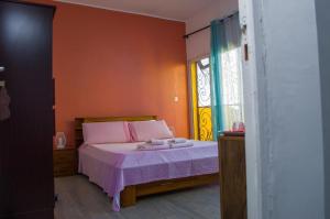 ein Schlafzimmer mit einem Bett mit violetter Bettwäsche und einem Fenster in der Unterkunft Room in Villa - The white-orange bedroom with a pleasant view overlooking the lake in Antananarivo