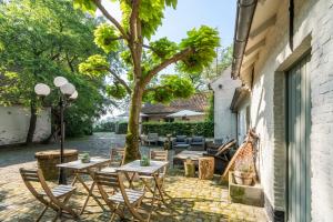 patio ze stołami, krzesłami i drzewem w obiekcie Fantastische vakantiewoning aan het bos w mieście Wingene