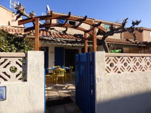 Joli Pavillon 2** Narbonne Plage في ناربون بلاج: بوابة زرقاء امام منزل به طاولة