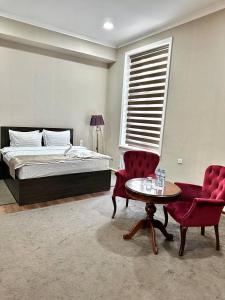 a bedroom with a bed and a table and chairs at Sofiya Tashkent Hotel in Tashkent